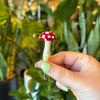 Hand holding a red and white glass mushroom spike