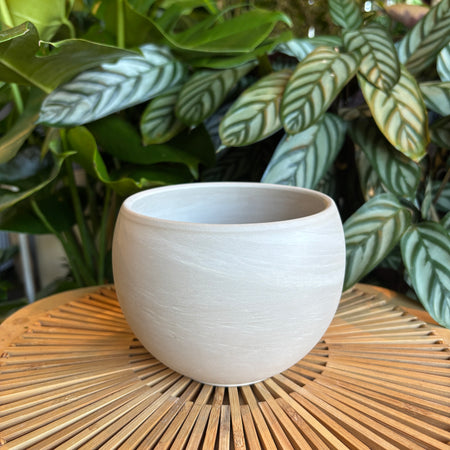 Empty white sphere planter on a woven tray