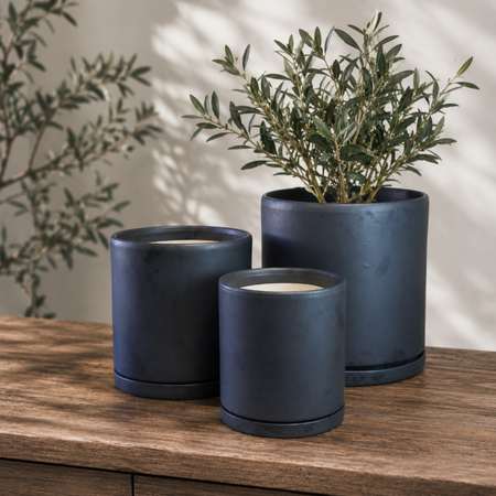 Three matte black cylinder pots with water trays and plants