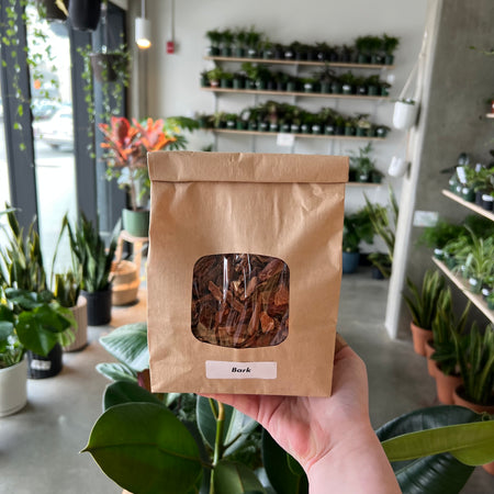 Hand holding a bag of bark in the shop
