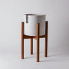 White planter on a medium stain bamboo plant stand